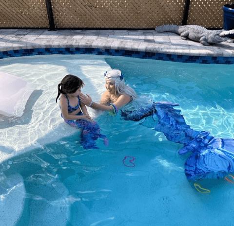 A mermaid swimming in a pool with a child